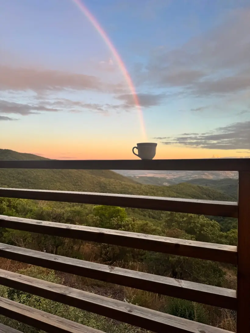 Kopje thee met een regenboog boven de heuvels