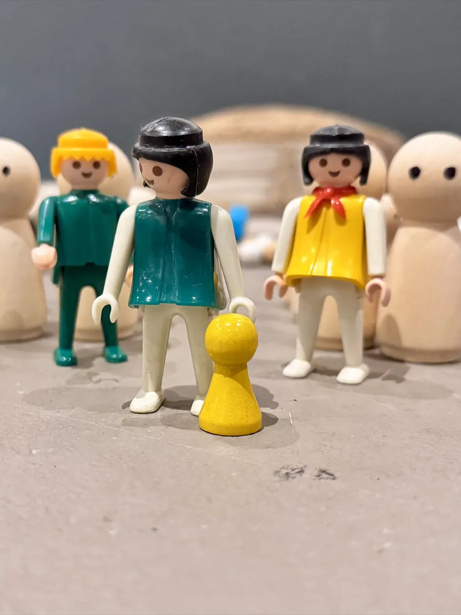 Speelgoedpoppetjes opgesteld als familie, met wazige houten poppetjes op de achtergrond
