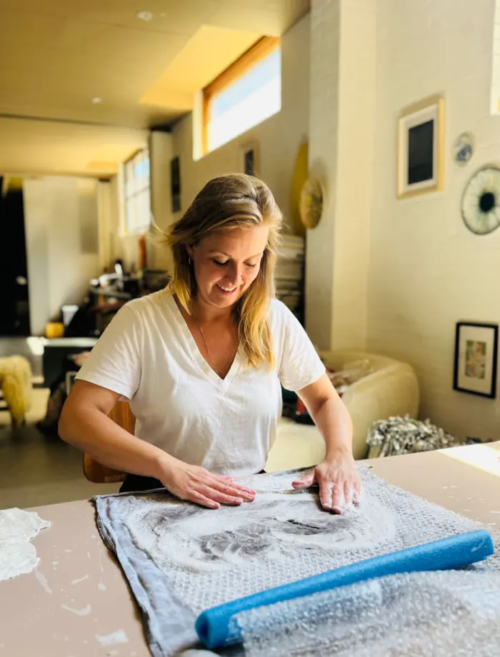 Carolina vilt met wol aan de werktafel in haar studio